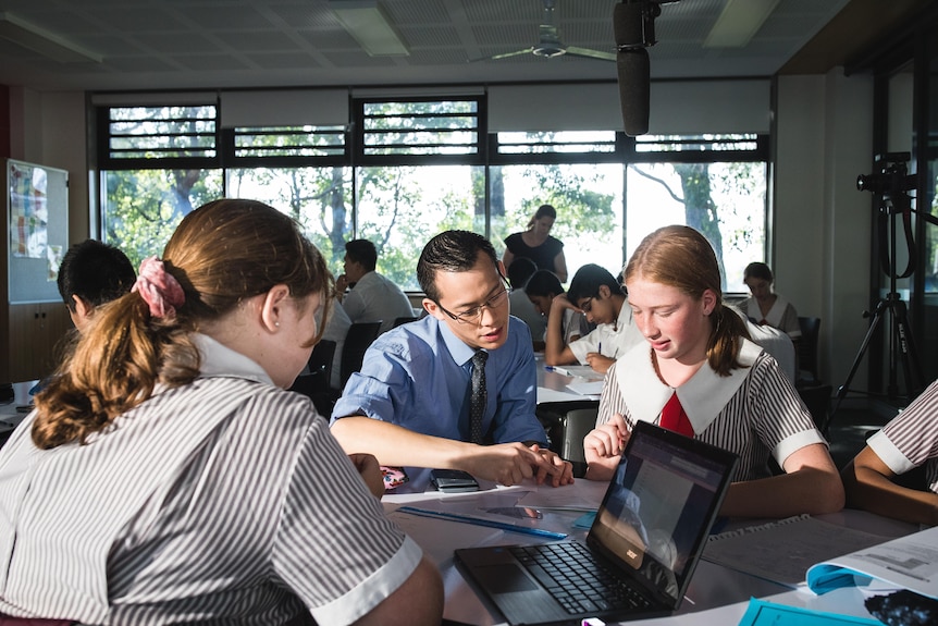 Asian male teacher working with female students 