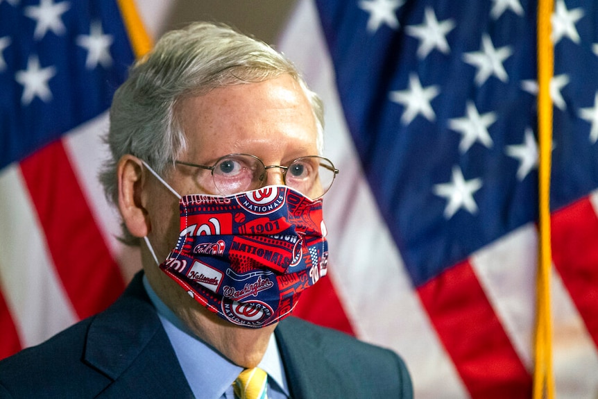 Senate Majority Leader Mitch McConnell listens to questions during a news conference while wearing a facemask