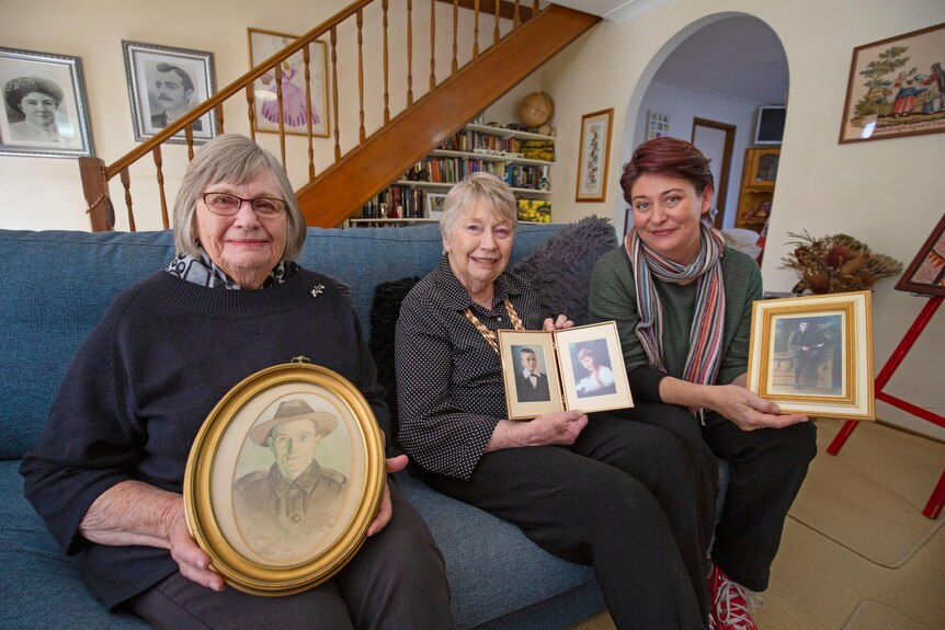 Pamela, Wendy and Kate holding photos of Harry Valentine and their brother Harry Frank. 