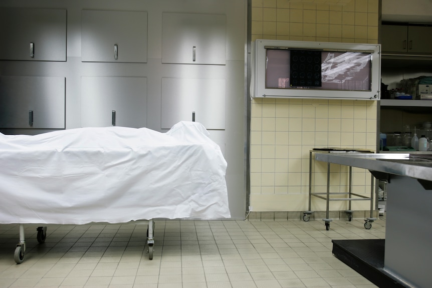 A dead body covered by a sheet in a hospital's morgue.
