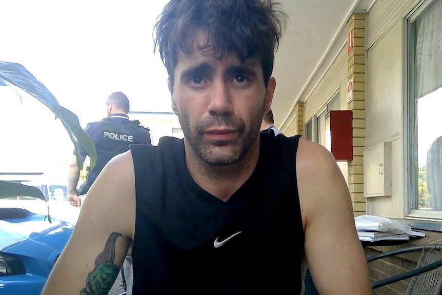 A man in a singlet looks at the camera.