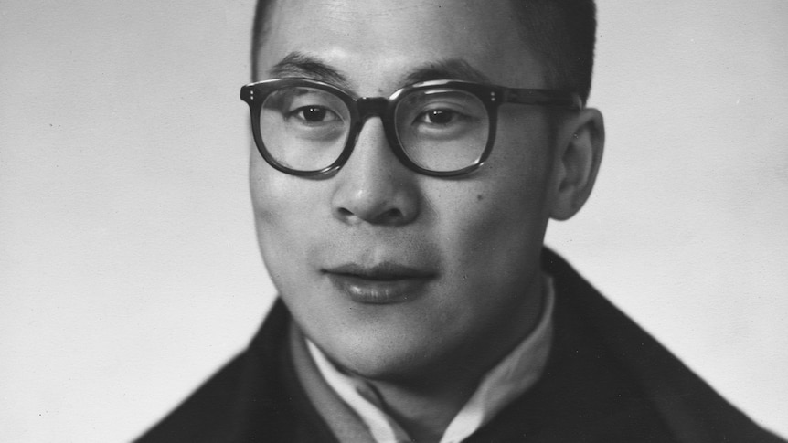 A young Dalai Lama, in dark rimmed glasses and robes