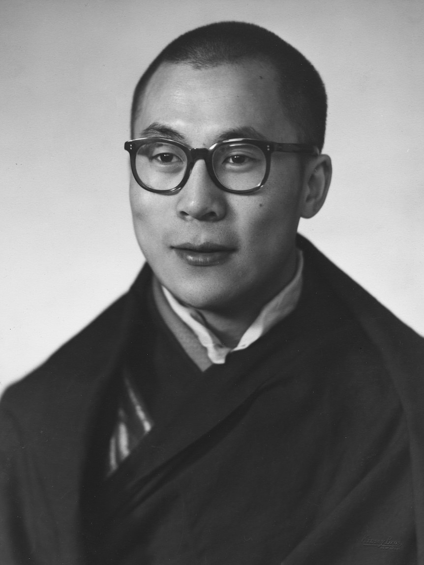 A young Dalai Lama, in dark rimmed glasses and robes