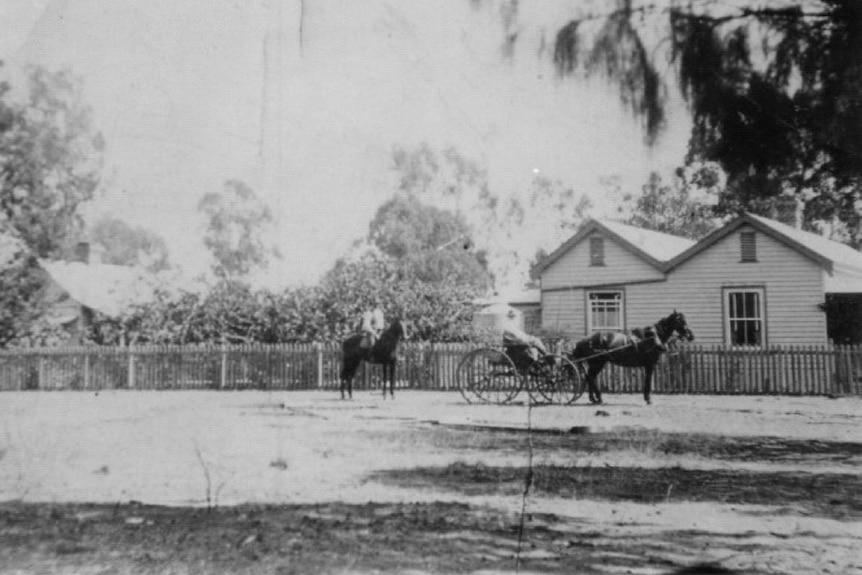 A black and white photograph of a house with horses 