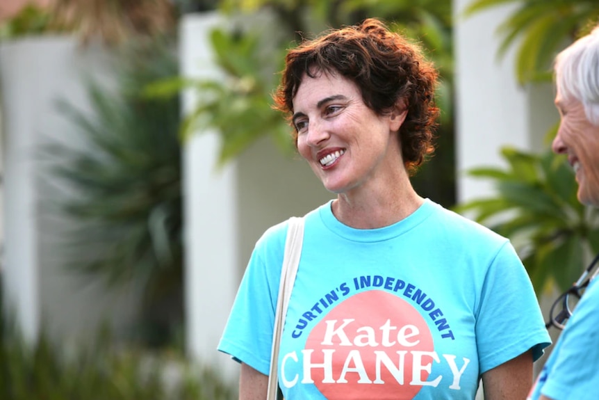 A dark haired lady in a blue/teal shirt saying Kate Chaney Curtin's Independent smiles as she talks to voters.
