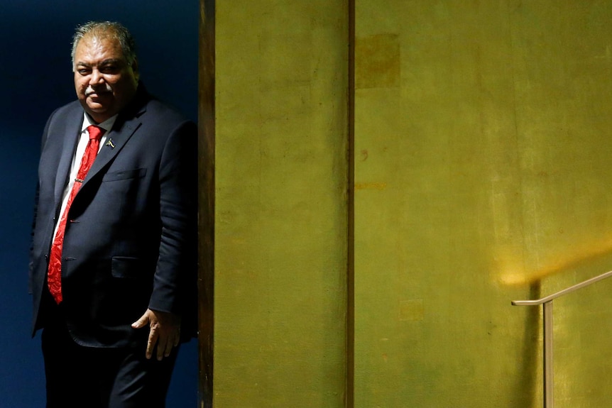 Baron Waqa stands behind a yellow wall, waiting to take the stage at a UN conference in New York