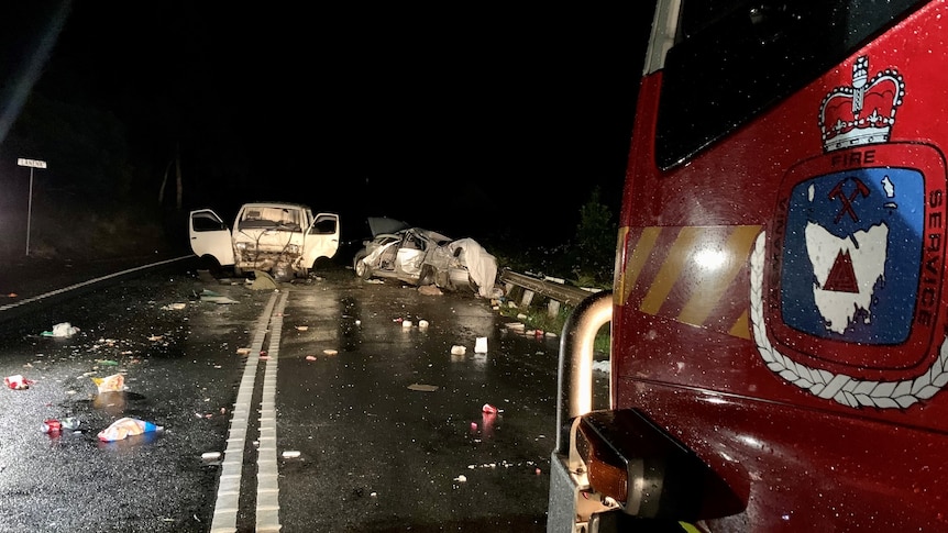 Two wrecked cars on a dark road.