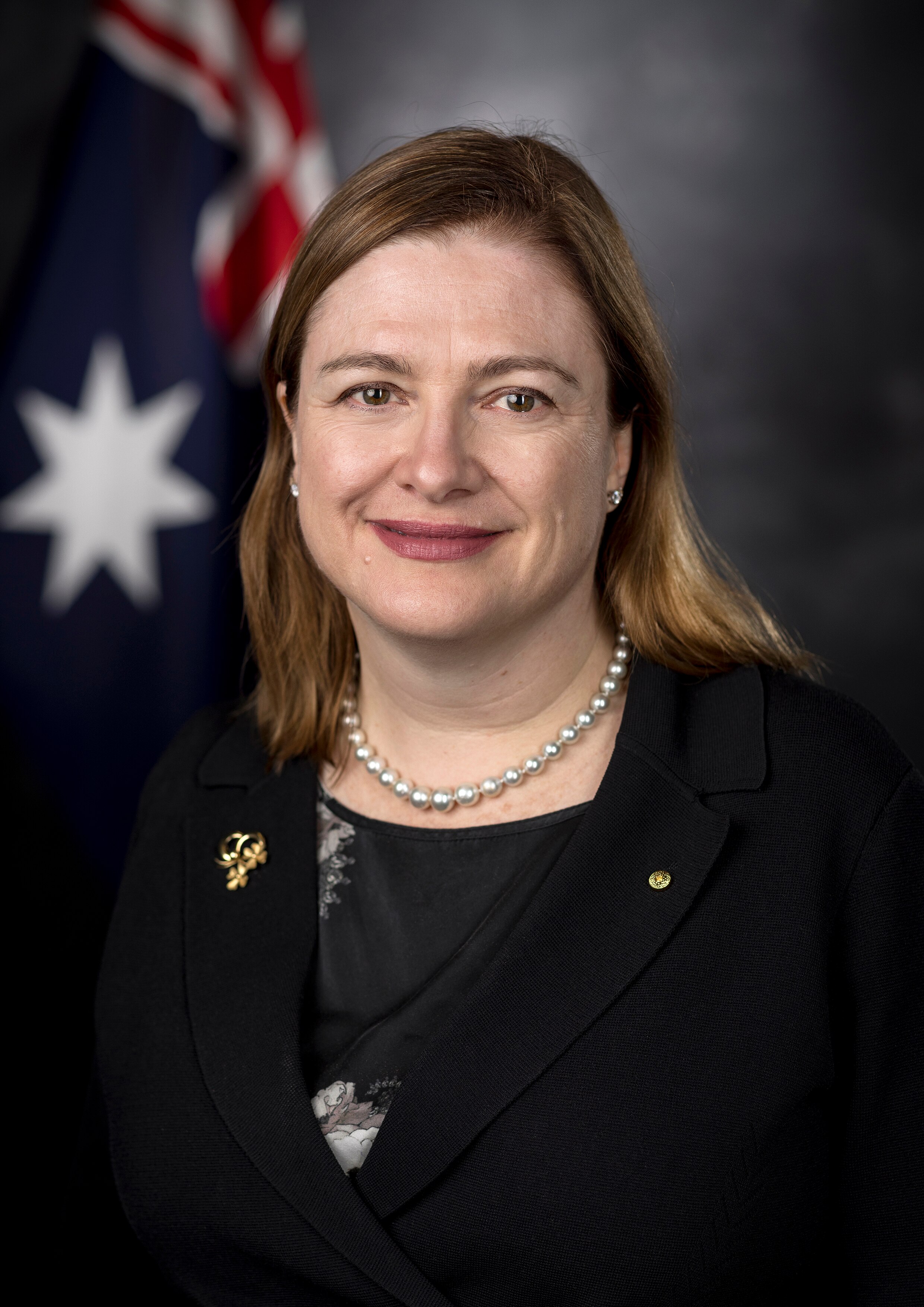 A woman smiling. An Australian flag can be seen behind her.