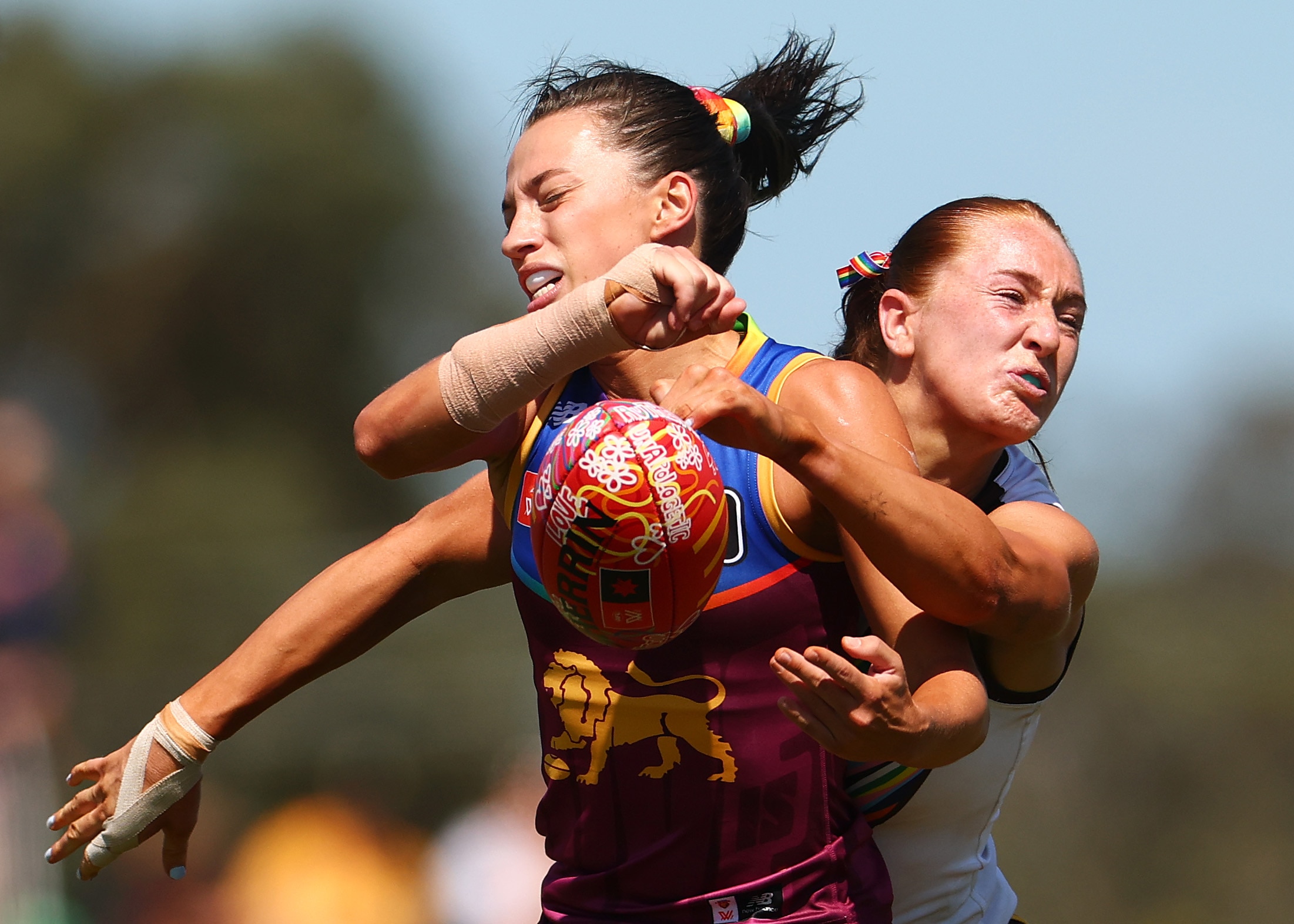 Jade Ellenger of the Lions handballs while being tackled by Mackenzie Eardley of the Hawks during an AFLW match.