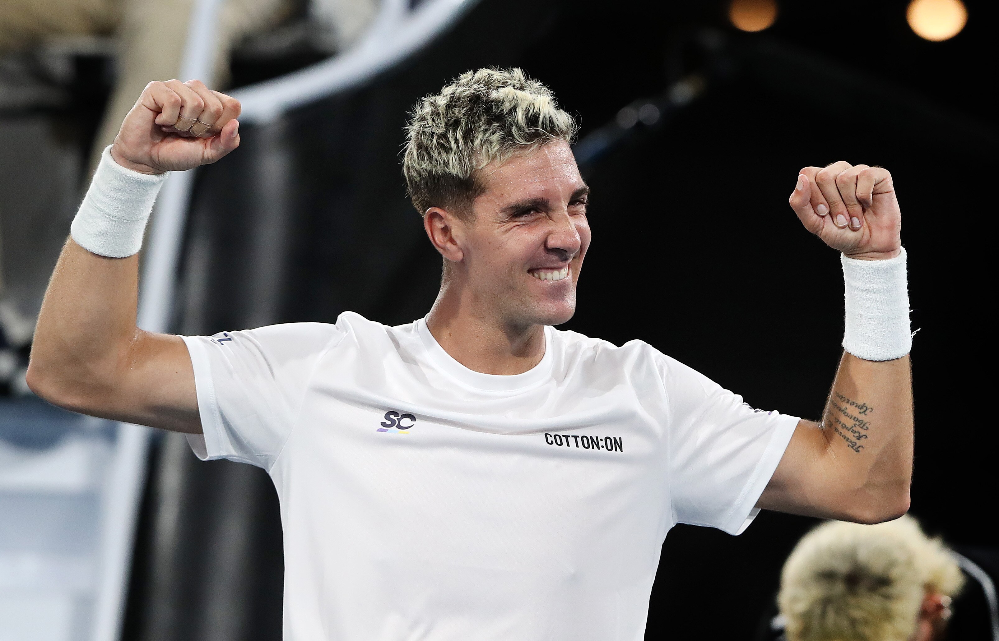 A man in a white shirt with his arms raised in fists