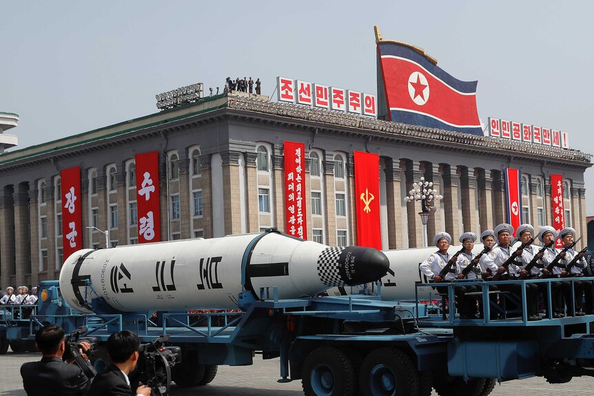 Military vehicles carry missiles at a parade the day before the failed test.