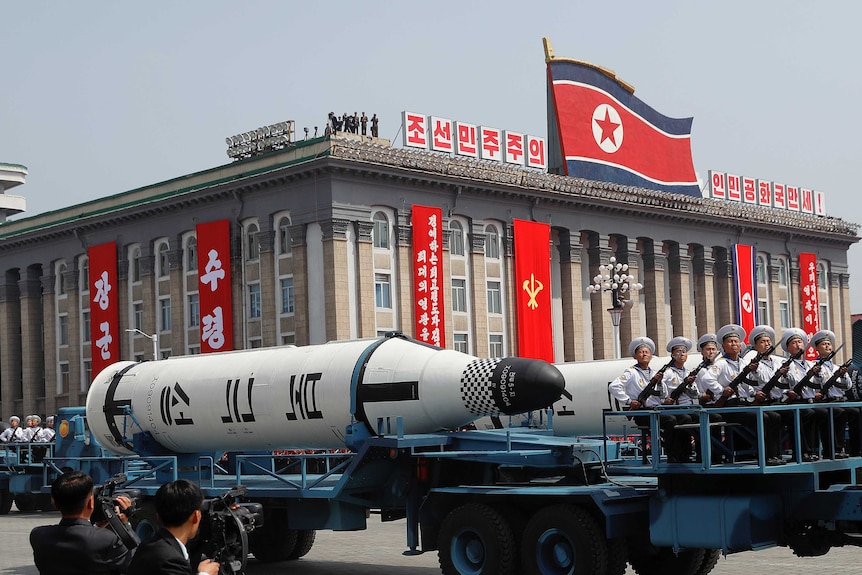 Military vehicles carry missiles with characters reading 'Pukkuksong' during a military parade.