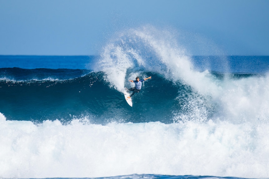 A professional surfer riding a wave, on top of it, cutting back against the rip