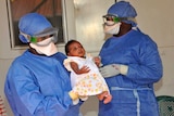 Medical workers present a baby who survived Ebola