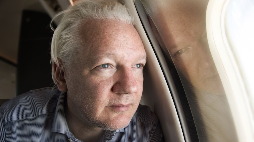 Julian Assange looking out of a plane window.