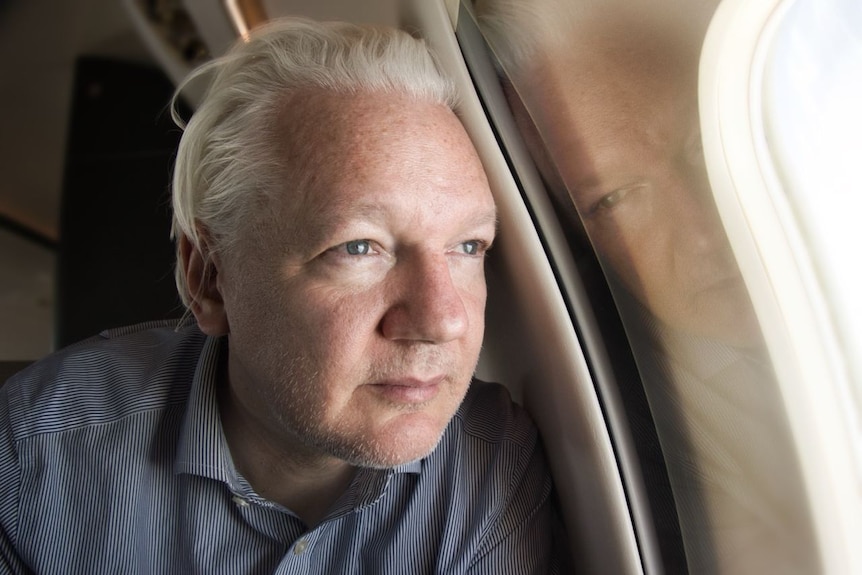 Julian Assange looking out of a plane window.