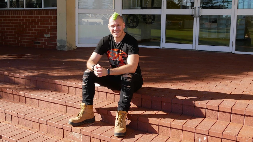 Author Holden Sheppard seated on stairs.