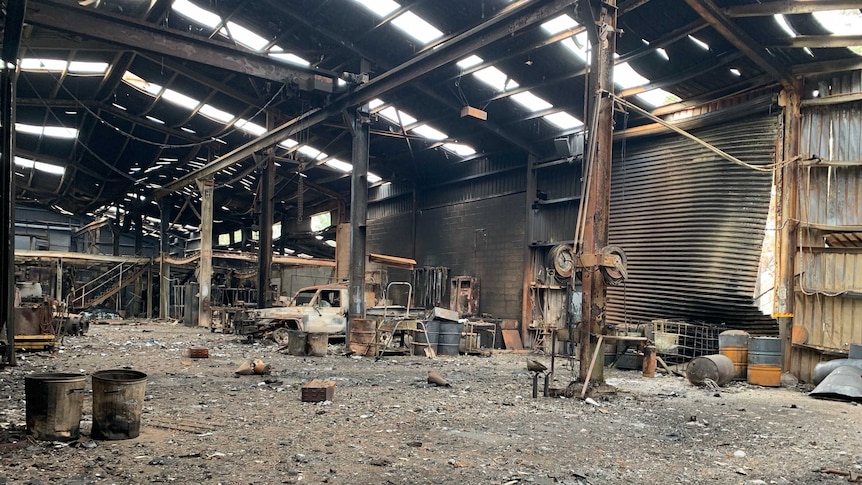 the inside of a shed has been burnt out with debris on the floor and burnt out metal