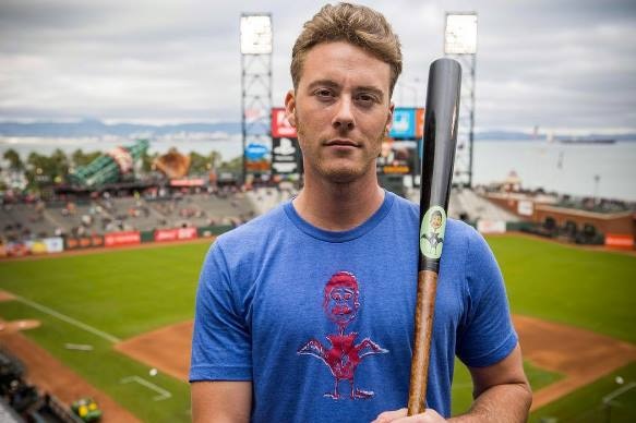 US baseballer Timothy Cusick holds a baseball bat in front of a diamond.