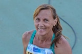 A woman in athletic clothing smiles on track.