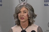 A woman with grey hair wearing a pink top