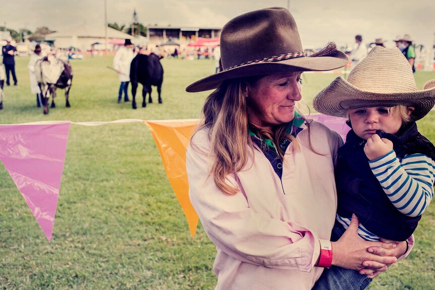 A woman holds her young son at a regional showground.
