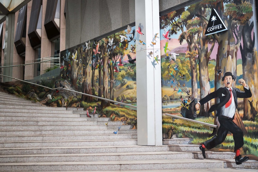 Colourful street art on a staircase in downtown Perth shows a cheerful man with birds flying out of his briefcase.