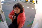 A woman in red jacket and black top at service station.