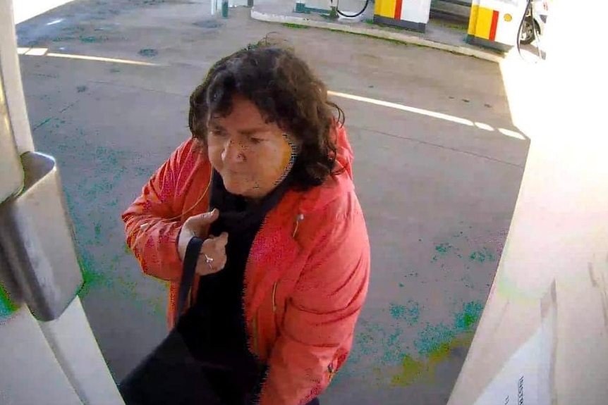 A woman in a bright jacket and a dark top at a service station.