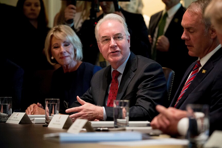 Tom Price sits beside Betsy DeVos and Ryan Zinke at a boardroom table in the White House
