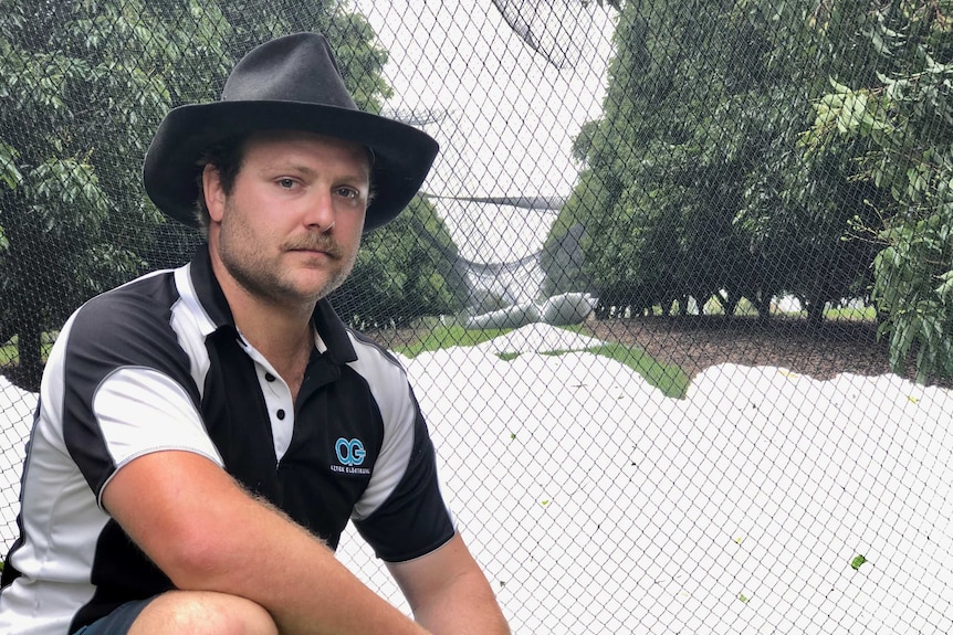 Lychee farmer knees in front of a large pile of hail.