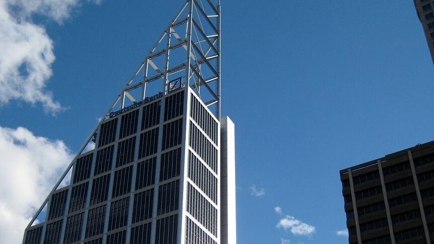 A glass and steel skyscraper with a triangular top is pictured against a bright blue sky.