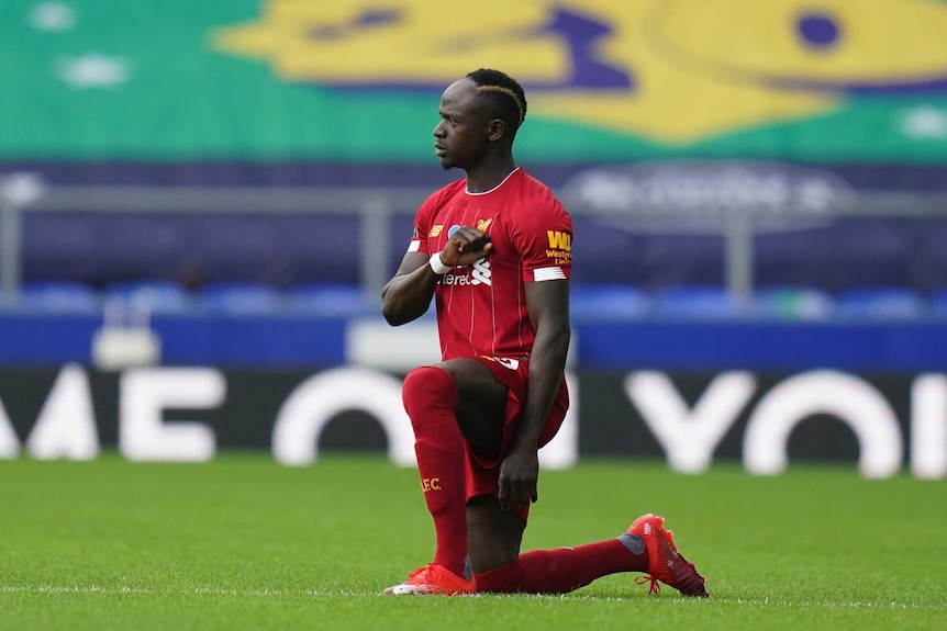 Liverpool player Sadio Mane kneels and puts his fist to his chest as part of a demonstration in support of Black Lives Matter.