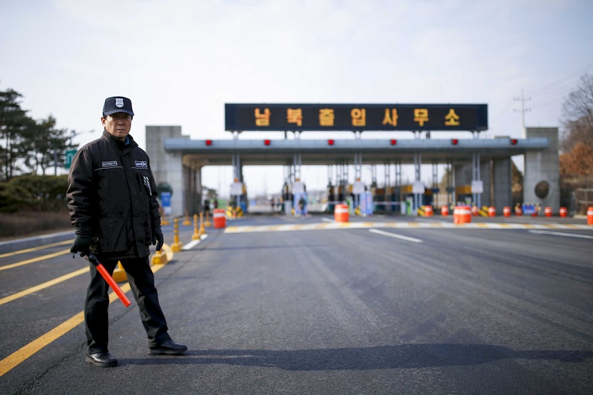 A man with a baton stands at a checkpoint on the Korean border