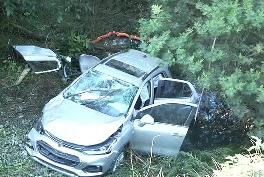 The badly damaged car has two doors missing and a smashed windscreen.