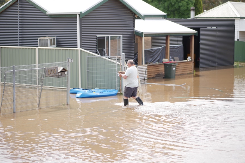 A man holding a birthday cake in a flooded street