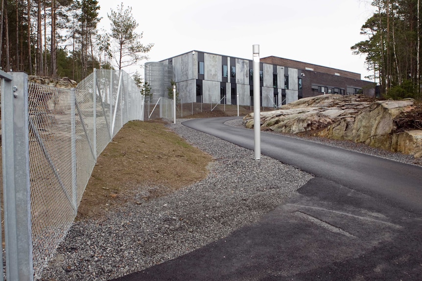 A asphalt road leads up to a concrete exterior of Halden prison in Norway.