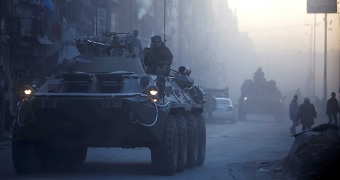 Russian soldiers ride on armoured vehicles through a street in Aleppo, Syria.