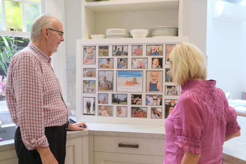 Two people looking at a board of family photos. 