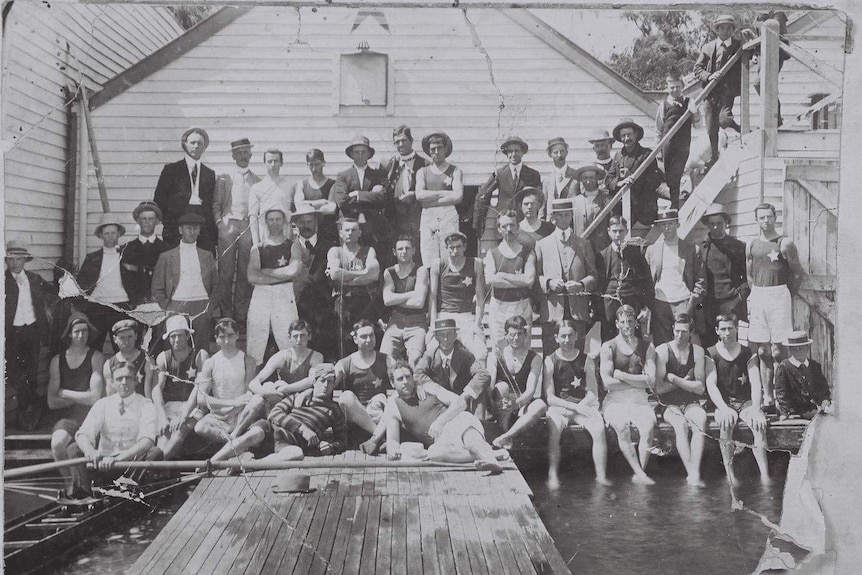 Rowers and other gentlemen in hats gather for a photo in 1911.
