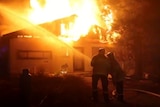 Firefighters hose a house as it burns.