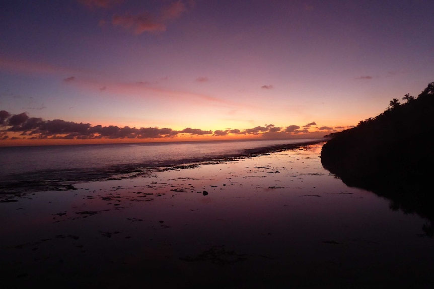 Purple sky during sunset over the water and sand