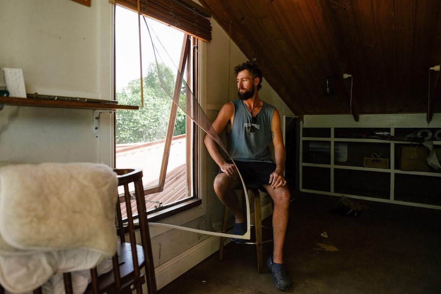 Joel gazes out the window of his "refuge room" which is an attic-like roof space