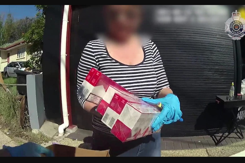 A woman holding several cartons of cigarettes 