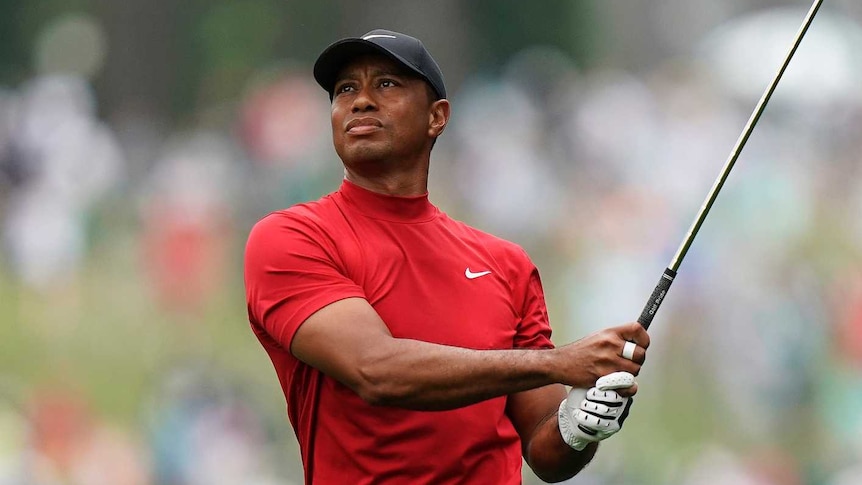 Tiger Woods, wearing his traditional red shirt and black pants, completes a drive in the final round of the Masters at Augusta.
