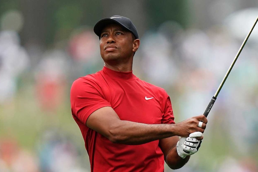 Tiger Woods, wearing his traditional red shirt and black pants, completes a drive in the final round of the Masters at Augusta.