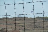 A huge North Korean flag as seen behind barbed wire within the De-Militarized Zone on the Northern side of the border.