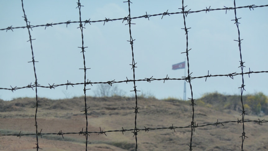 A huge North Korean flag as seen behind barbed wire within the De-Militarized Zone on the Northern side of the border.