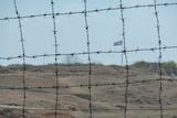 A huge North Korean flag as seen behind barbed wire within the De-Militarized Zone on the Northern side of the border.