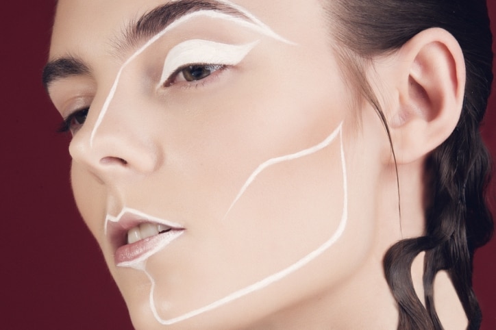 A make-up model with white lines on face.